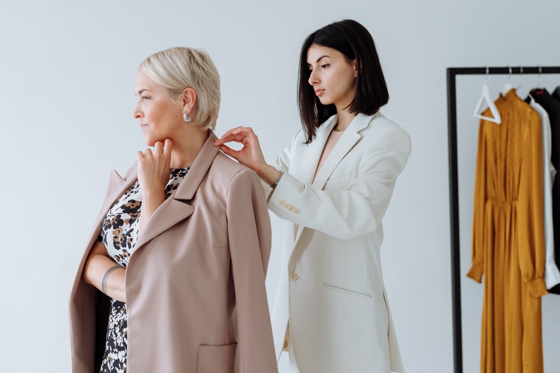 Woman in White Blazer Standing Beside Woman in Black and White Floral Shirt